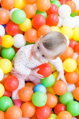 Fototapeta na wymiar Beautiful baby girl playing with colorful balls