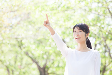 指差しをする女性、新緑