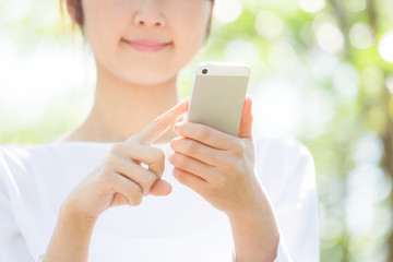 スマートフォンで検索する女性、新緑