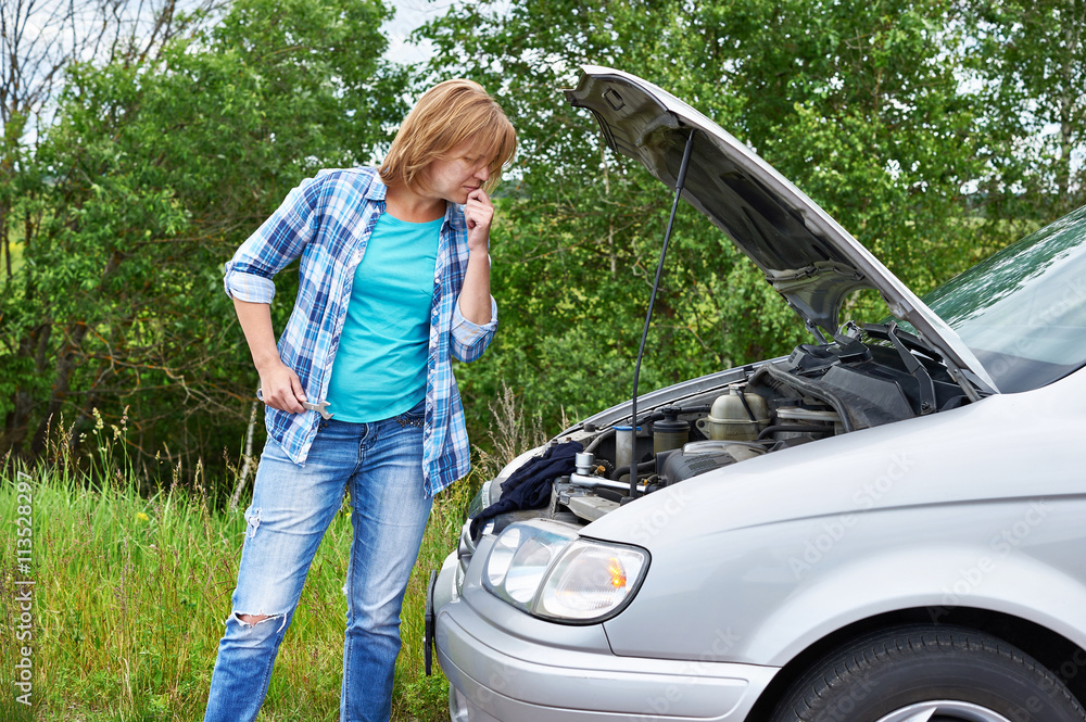 Wall mural Woman with wrench near broken car