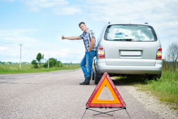 Man standing on road near car waiting help