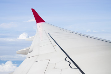 Plane wing on cloudy blue sky background