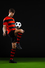 Soccer player kicking ball over black background