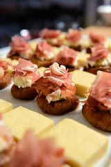 Close-up photo of cold appetizer with marinated figs, prosciutto