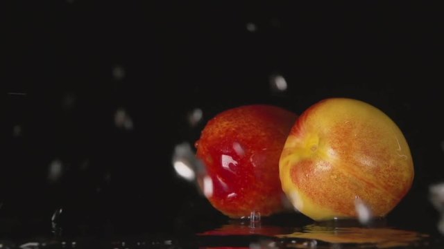 SLOW MOTION: A water flow falls on a nectarines on a black background