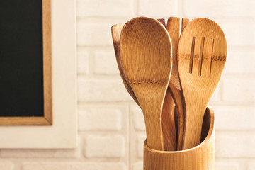Wooden kitchenware in the kitchen in a wooden Bank in front of a white brick wall