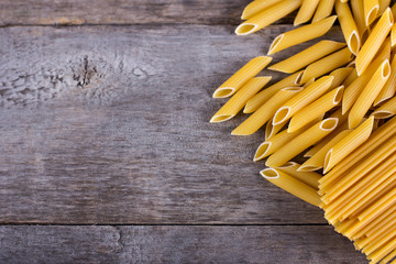 .macaroni, spaghetti on an old wooden table. Mix of pasta. close up portrait of raw homemade italian pasta, macaroni, spaghetti, and fettuccine.