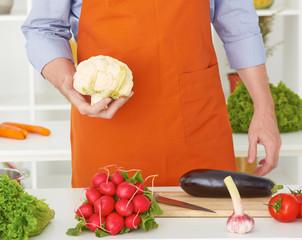 Mid section of a man preparing to chop cauliflower in the kitchen at home.