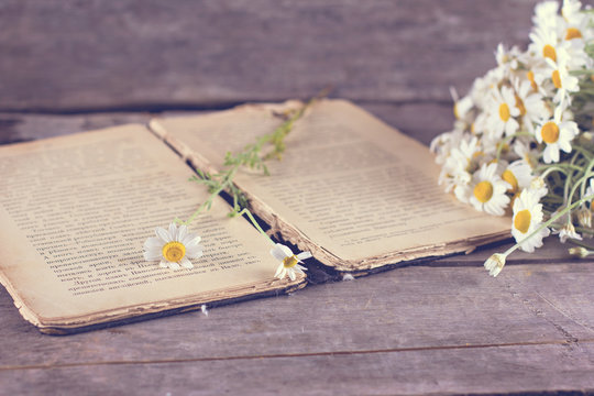 bouquet of daisies and an old book. Summer still life composition. Vintage books with bouquet of flowers/ nostalgic vintage background.
