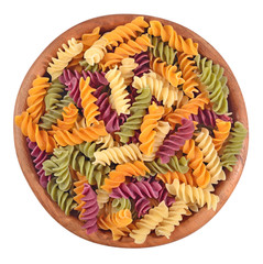 Colored uncooked italian pasta fusilli in a wooden bowl on a whi