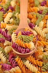 Colored uncooked italian pasta fusilli in a spoon