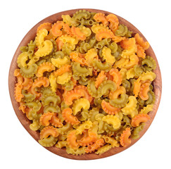 Colored uncooked italian pasta in a wooden bowl on a white