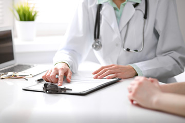 Close up of doctor and  patient  sitting at the desk near the window in hospital