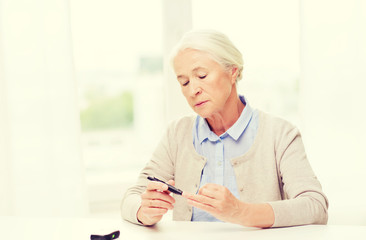 senior woman with glucometer checking blood sugar