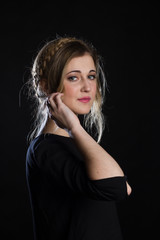 Beautiful blond girl with blue-green eyes on a black background. She wears a black t-shirt. 