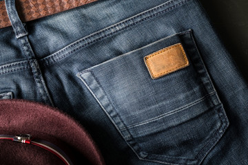 Back pocket of blue jeans with leather belt and fedora hat