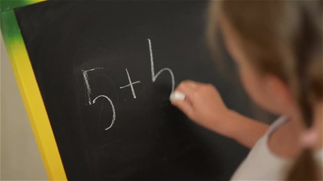 Schoolchild Practicing simple math on chalk board