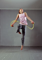 Healthy young muscular teenage girl skipping rope in studio. Child exercising with jumping on grey background.