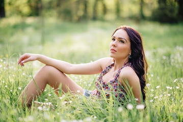 Naklejka na ściany i meble sunny summer day, a beautiful young woman lying on the grass