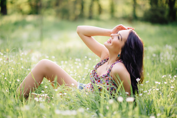 Naklejka na ściany i meble sunny summer day, a beautiful young woman lying on the grass