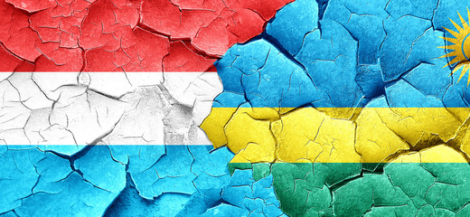 Luxembourg flag with rwanda flag on a grunge cracked wall