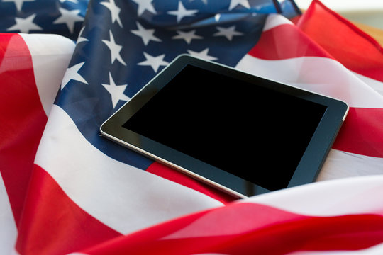 close up of tablet pc computer on american flag