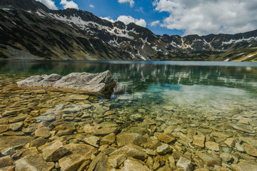 Mountains reflection in alpine lake at sunny day
