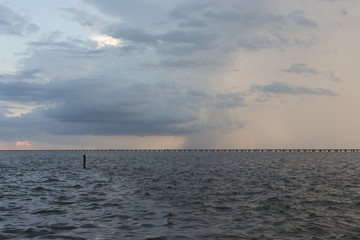 Stormy rainclouds over dark water, Lake Pontchartrain bridge early sunset