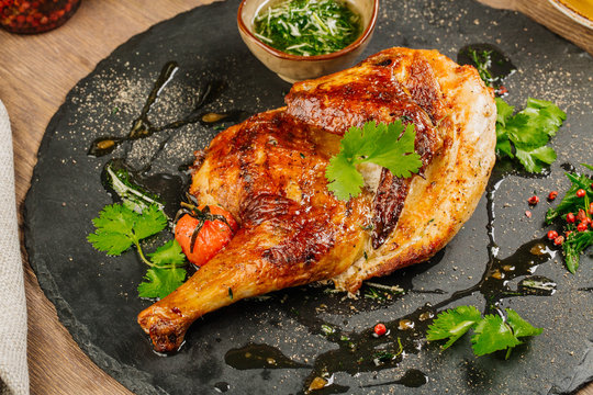 chicken Tabaka with sauce on stone plate.