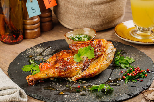 chicken Tabaka with sauce on stone plate.