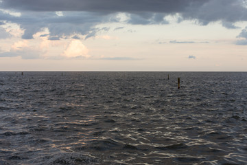 Soft afternoon light shining on dark lake water, underneath grey storm clouds