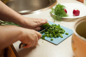 Naklejka na ściany i meble Woman cutting vegetables with a knife . женщина режет овощи ножом