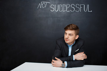 Picture of a sad man over black board with text not successful