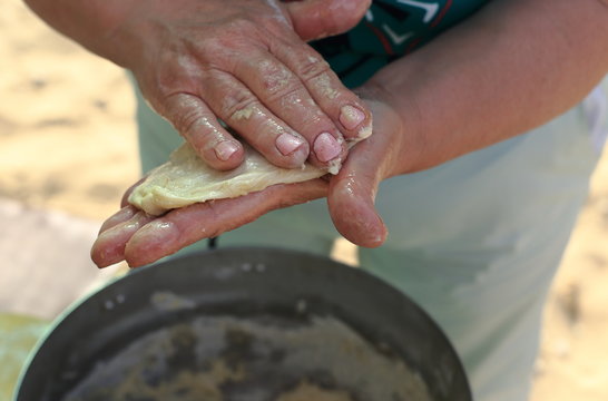 
woman's hand close-up. dough in his hands and does pizza. in the pan is big dough
