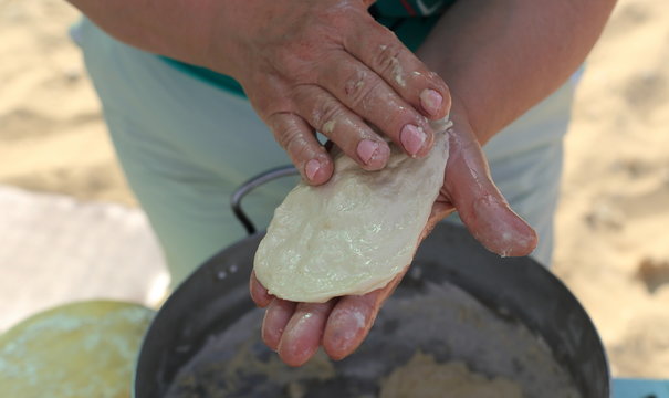 
woman's hand close-up. dough in his hands and does pizza. in the pan is big dough
