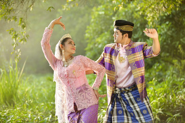 Asian Muslim man and woman wearing traditional dress in dancing action