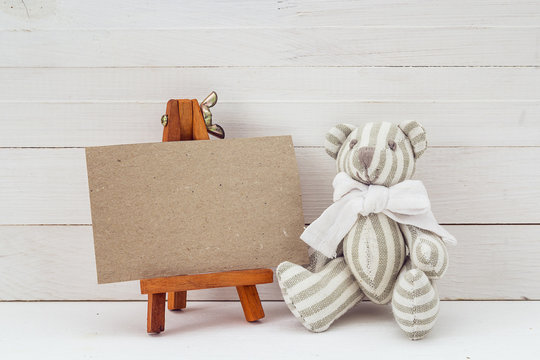 Blank card on a miniature easel and teddy bear.