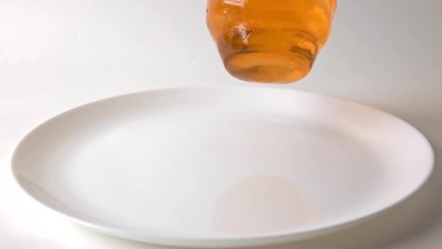 Super slow motion video of orange jelly falling on white plate