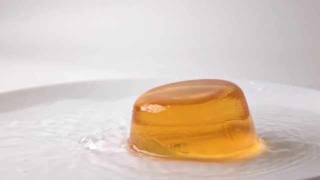 Macro super slow motion video of orange jelly falling in water