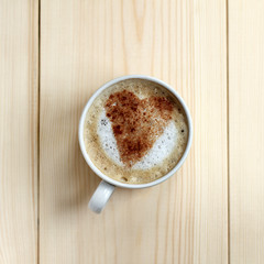favorite coffee with milk and cinnamon/ frothy coffee with cinnamon sprinkled in heart shape, bright wooden background top view 