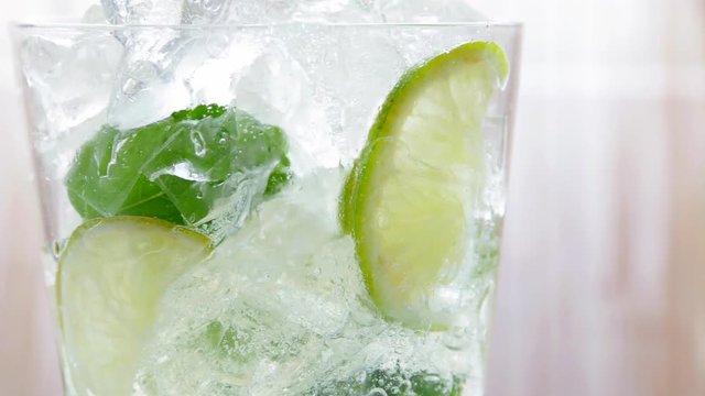 Mojito cocktail drink is poured into a glass