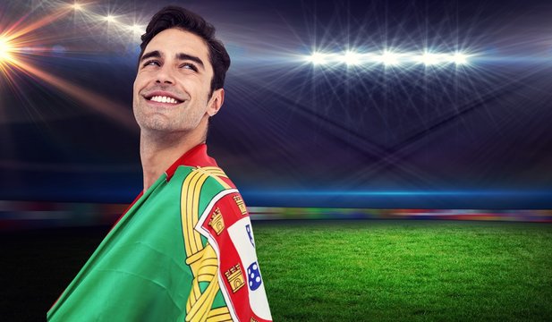 Athlete with portuguese flag wrapped around his body against rugby stadium