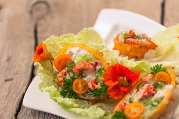 Exotic Shrimp salad served in n half a kiwano and leaves of the Chinese cabbage for summer party on wooden table, selective focus, copy space