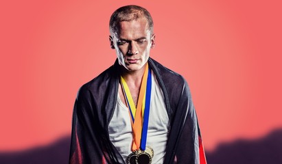 Athlete with german flag wrapped around his body against orange