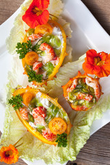 Exotic Shrimp salad served in n half a kiwano and leaves of the Chinese cabbage for summer party on wooden table, selective focus, copy space