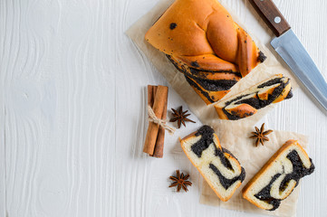 Poppy seed roll on a white wooden surface. Copyspace, top view.