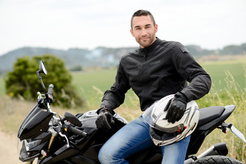 Naklejka premium przystojny młody mężczyzna rowerzysta z białym kasku na czarnym motocyklu