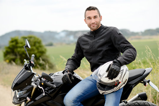 Fototapeta handsome young man biker with white helmet riding black motorcycle