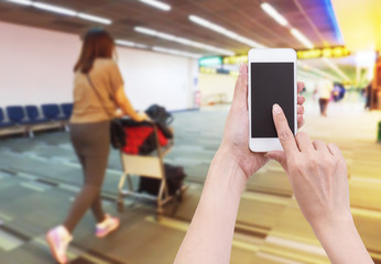 Hand holding mobile phone with Blurred image of passenger pushin