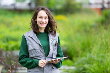 Young attractive woman working in a public garden using tablet